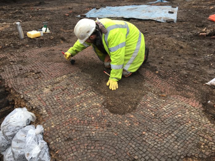 Archaeologist Richard Huxley carefully cleans the mosaic pavement. Credit: Mathew Morris/ University of Leicester