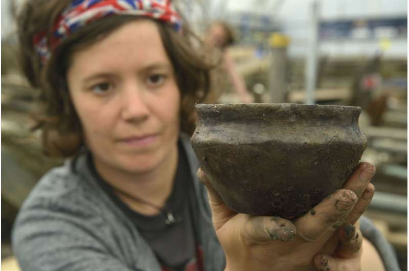 Archaeologist from of the Cambridge Archaeological Unit on site at the Must Farm excavation in 2016 displays a pot recovered from the ' class=